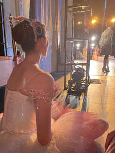 a woman in a ball gown sitting on the floor with her back to the camera