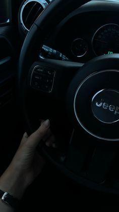 a person driving a car in the dark with their hand on the steering wheel