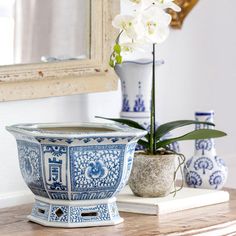 a blue and white planter sitting on top of a table next to a mirror