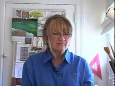 a woman wearing glasses standing in front of a window with papers on the wall behind her