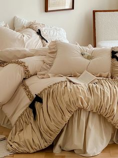 an unmade bed with ruffled sheets and pillows