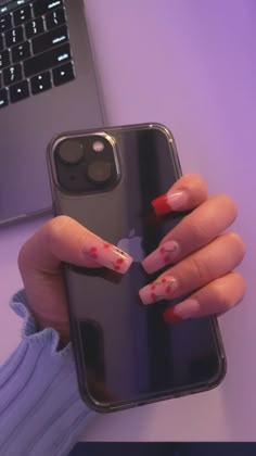 a woman's hand holding an iphone case with red and white designs on it