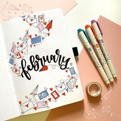 an open notebook with the word february written in cursive writing on it next to two pens