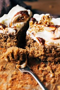 a piece of carrot cake with white frosting and walnuts on top is being cut by a fork