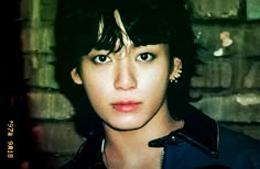 a close up of a person near a brick wall with blue eyes and piercings