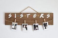 a wooden sign that says sisters hanging on clothes pegs with photos pinned to it