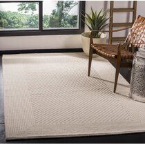 a white rug with a chair and window in the background