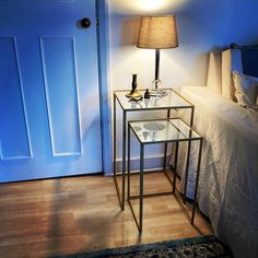 a bedroom with a blue door and two glass tables on the floor next to it