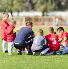 a group of young boys sitting on top of a soccer field next to each other