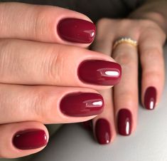 a woman's hand with red nail polish holding onto her manicured nails and gold ring