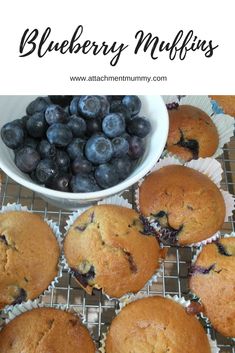 blueberry muffins on a cooling rack next to a bowl of blueberries