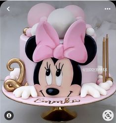 a minnie mouse cake with pink and white icing on a gold plated stand