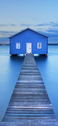 a blue house sitting on top of a wooden pier