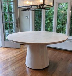 a white table sitting in the middle of a room with windows and wooden flooring