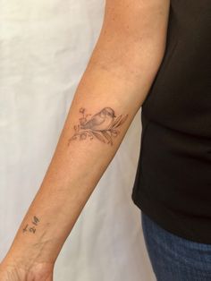 a woman's arm with a bird tattoo on the left side of her arm