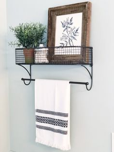 a towel rack with two towels hanging from it's sides next to a potted plant