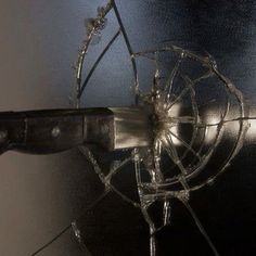 a broken glass door with a knife sticking out of it's center hole and the handle missing