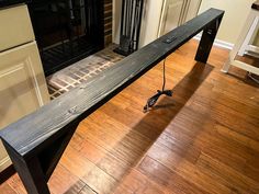 a wooden bench sitting on top of a hard wood floor next to a fire place