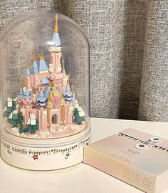 a toy castle under a glass dome on top of a table next to a book