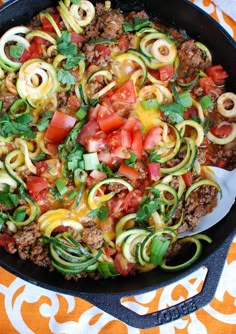 a skillet filled with zucchini, meat and vegetables