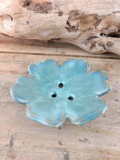 a blue flower brooch sitting on top of a wooden table