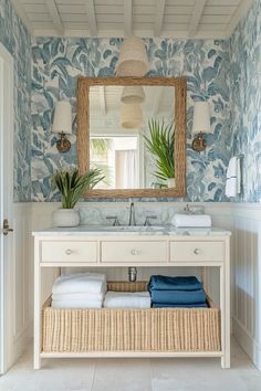 a bathroom with blue and white wallpaper and a large mirror above the vanity area