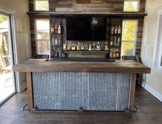 the bar is made out of wood and has bottles on it