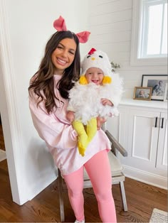 a woman holding a baby wearing a chicken costume