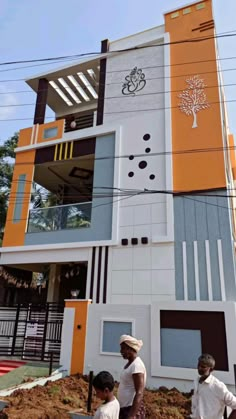 two men are standing in front of a building that has been painted orange and white