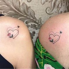 two women with matching tattoos on their legs, one has a heart and the other has a flower