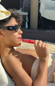 a woman laying on top of a towel next to a red toothbrush in her mouth