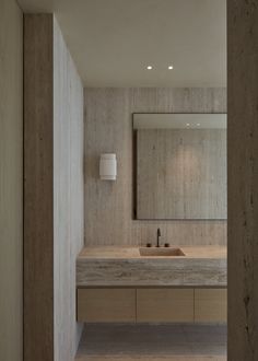 a bathroom sink sitting under a large mirror next to a wall mounted faucet