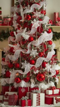 a christmas tree decorated with red and white ribbons, ornaments and presents under the tree