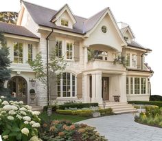 a large white house with lots of windows and plants in front of the entrance to it