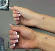 two hands with white nail polishes and stars on their fingers, both holding each other