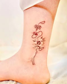 a woman's foot with a flower tattoo on the side of her leg and an arrow