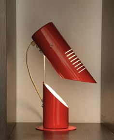 a red desk lamp sitting on top of a wooden table