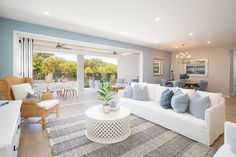 a living room filled with white furniture and lots of blue pillows on top of it