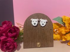 there is a small wooden clock with two dogs on it and flowers in the background