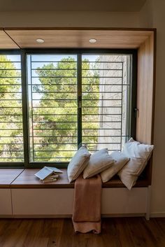 a window sill with pillows on it in front of a large window overlooking trees