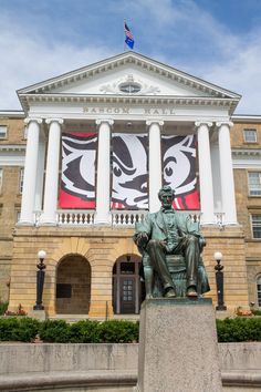 a statue sits in front of a building with flags on it's walls and columns