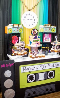 a table topped with an old school cassette cake and cupcakes on top of it