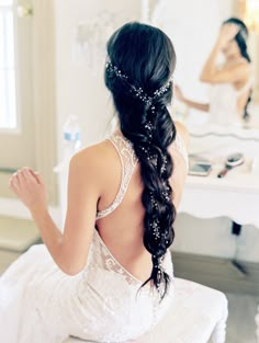 the back of a bride's dress as she sits in front of a mirror