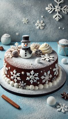 a cake decorated with frosting and snowflakes on a blue table next to cinnamon sticks