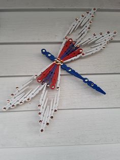 a clock made out of toothpicks and beads on a white wooden surface with red, white and blue colors