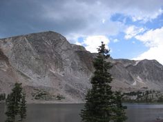 there are some trees in the foreground and mountains in the background