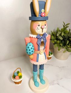 a rabbit figurine is standing next to a potted plant and some eggs