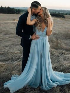 a man and woman are kissing in the middle of an open field with tall grass