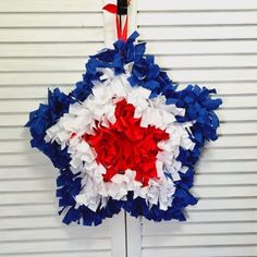 a red, white and blue wreath hanging on the side of a building in front of a garage door