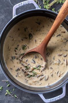 a wooden spoon in a pot filled with mushroom gravy on top of a table